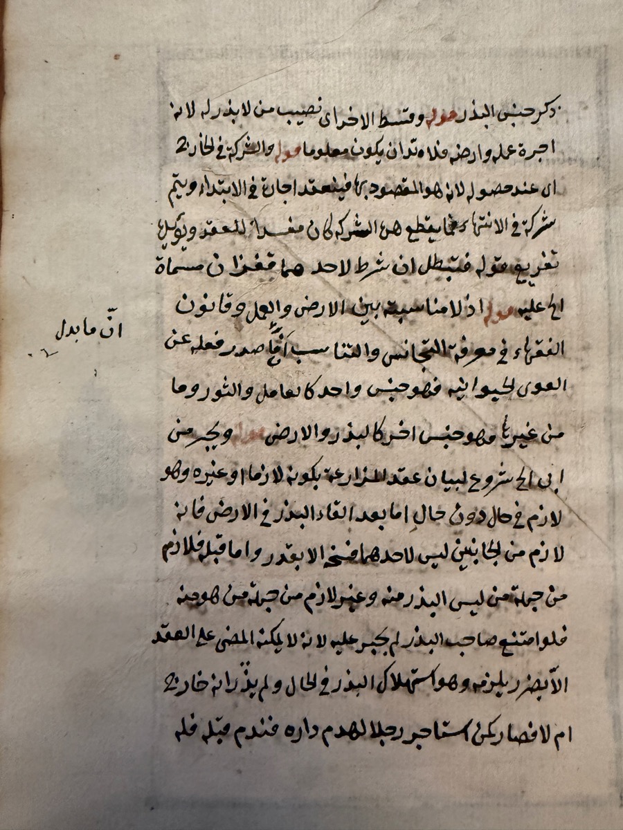 The back of the same sheet: fifteen lines of Arabic handwriting in black ink with a few words in red and a note in the margin, on creased old paper.